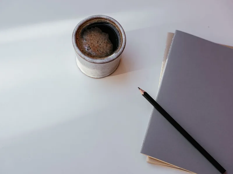 Tasse de café, carnet et crayon posés sur une table, pour prendre en note les mesures d'un test